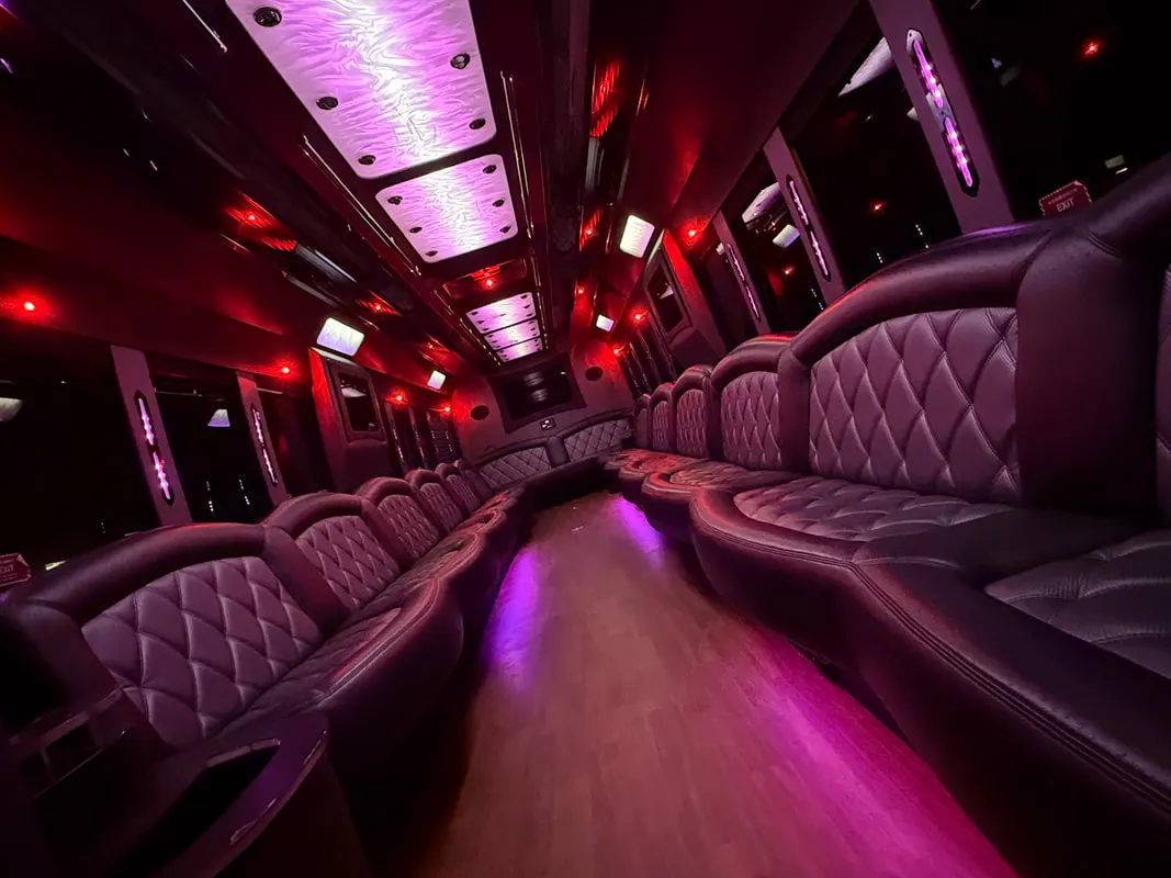Freightliner Party Bus interior with perimeter lounge seating, LED ceiling lighting and wood-look flooring for limo rental in North Attleboro, MA