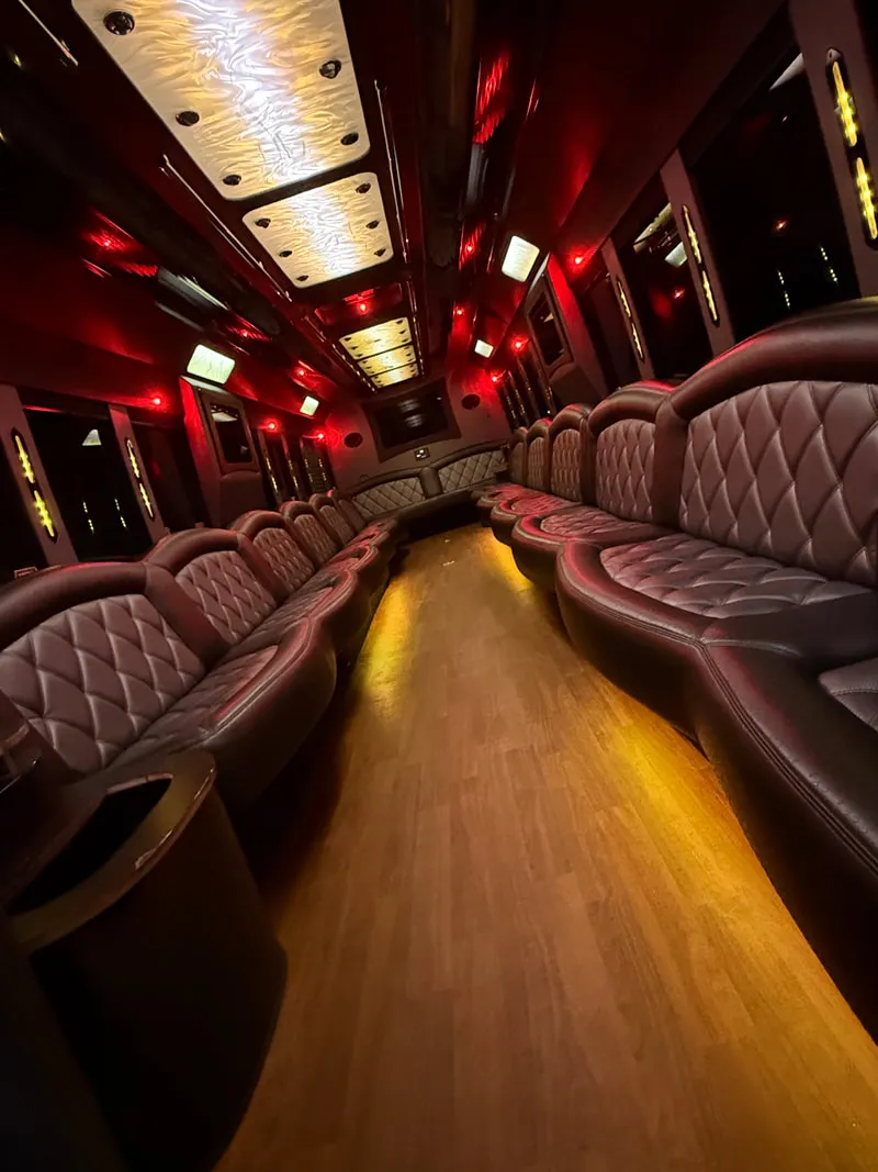 Freightliner Party Bus interior with perimeter lounge seating, LED ceiling lighting and wood-look flooring, photo 12 for limo rental in North Attleboro, MA