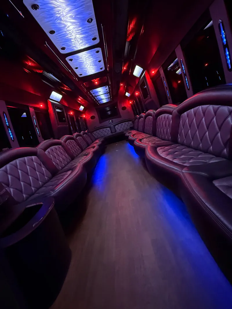 Freightliner Party Bus interior with perimeter lounge seating, LED ceiling lighting and wood-look flooring, photo 8 for limo rental in North Attleboro, MA