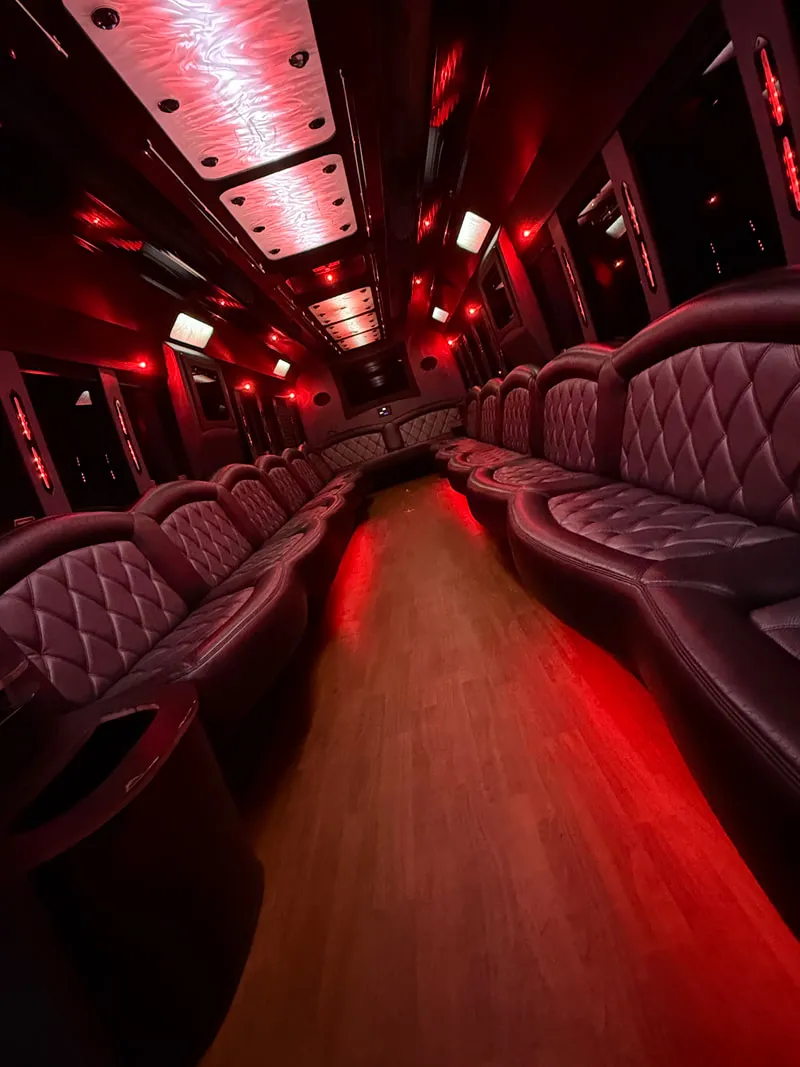 Freightliner Party Bus interior with perimeter lounge seating, LED ceiling lighting and wood-look flooring, photo 9 for limo rental in North Attleboro, MA