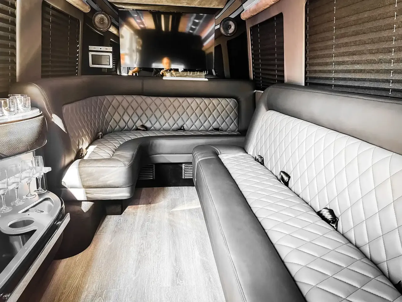 Mercedes-Benz Sprinter Limousine rental, interior view: perimeter lounge seating, window shades and wood-look flooring