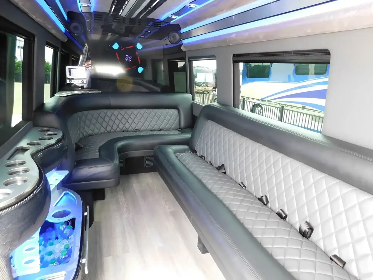 Mercedes-Benz Sprinter Limousine rental, interior view: perimeter lounge seating, LED accent lighting and wood-look flooring