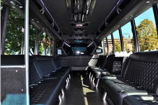 Mini Coach Limousine Bus interior with perimeter lounge seating and dance pole for limo rental in Manchester, NH