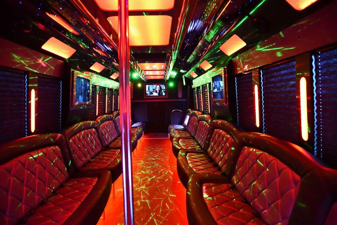 50 Passenger Party Bus interior with perimeter lounge seating, window shades and LED accent lighting for limo rental in Queens Village, NY