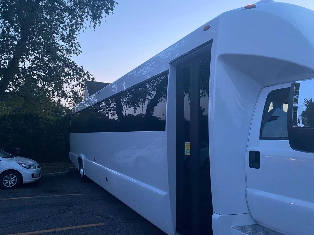 White 25 Passenger Party Bus exterior with tinted windows for limo rental in South Richmond Hill, NY